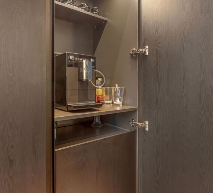 Moderne keuken Someren, keukenstudio Someren, keuken op maat someren, Keramisch werkblad, Kookeiland, kastenwand, , Geïntegreerde Bora kookplaat met afzuiging, Franke Fragranite witte vlakinbouw spoelbak, Quooker kraan Flex chroom, Zwart houtdecor fronten, Zwarte horizontale en verticale greeplijsten. Koffie corner keuken.