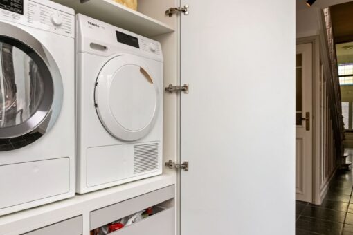 Wasmachinekast op maat, maatwerk wasmachinekast, maatwerk bijkeukenkast, bijkeukenkasten op maat, Moderne keuken Oosterhout, keukenstudio Oosterhout, keuken op maat Oosterhout, Moderne keuken Breda, keukenstudio Breda, keuken op maat Breda, composiet werkblad, hoekopstelling, Geïntegreerde Bora kookplaat met afzuiging, rvs vlakinbouw spoelbak, Gelakte fronten, push-to-open, Tip-On, wasmachinekast op maat, wasmachine op hoogte.